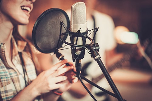 A woman in front of a microphone recording music