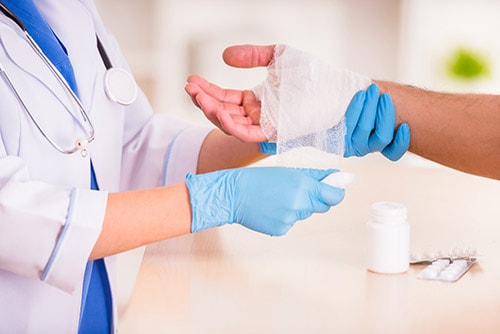 A nurse bandaging the hand of a patient with gauss