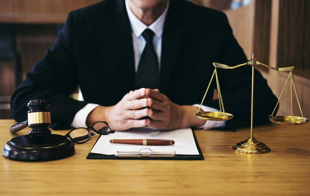 Photo of a lawyer at his desk with a balance and gravel