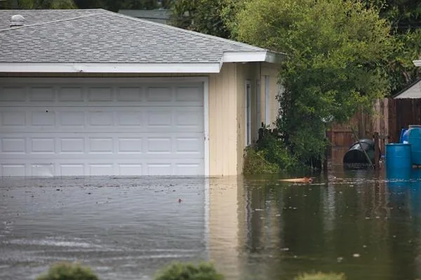 Photo of a garage with flood waters a few feet higher than the foundation of the house