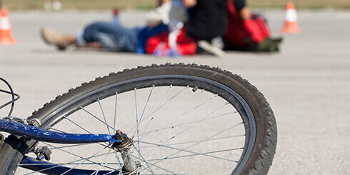 Photo of a bike in the foreground with a paramedic attending to an injured person in the background