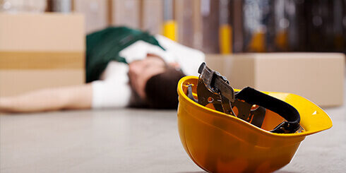 Photo of a worker lying on the floor with his helmet on the ground in the foreground