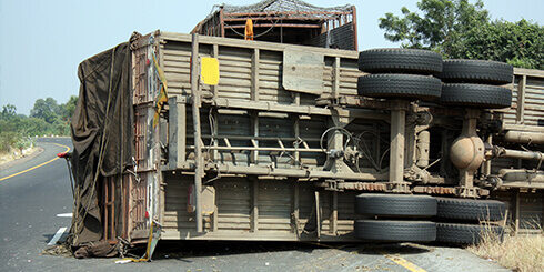 Photo of a tractor trailer turned on it's side in the middle of the road