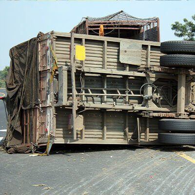 Photo of a tractor trailer turned on it's side in the middle of the road