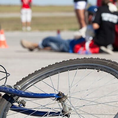 Photo of a bike in the foreground with a paramedic attending to an injured person in the background
