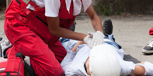 Photo of a paramedic practicing performing CPR on a person on the ground