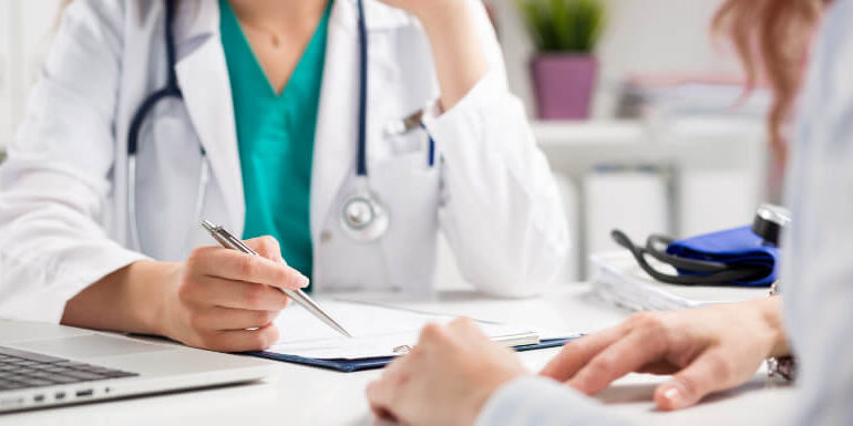 Photo of a doctor speaking with a patient while writing down some notes