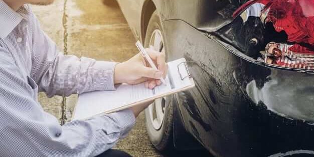 Insurance agent takes notes during a car accident claim process